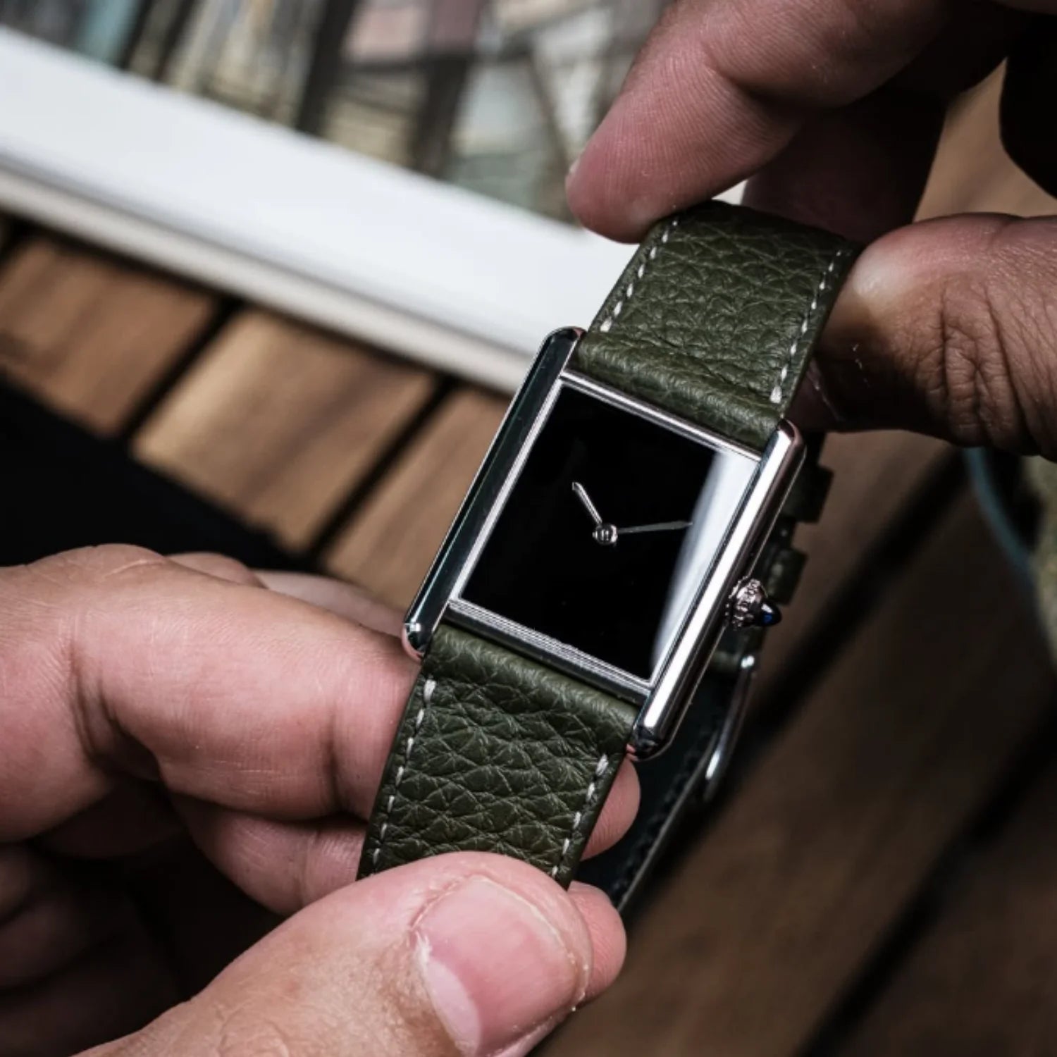 Angled shot of the CILOA numberless black square watch showing the textured green leather band and the detailed silver crown setting