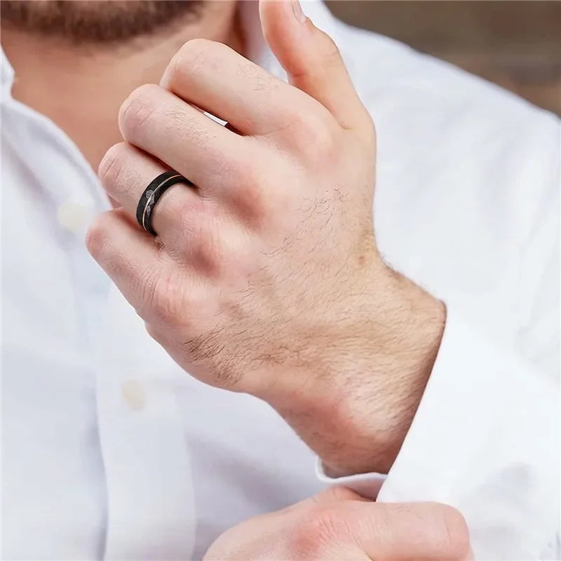 Close-up of a man adjusting his white dress shirt cuff, showcasing the Tigrade black hammered tungsten wedding band on his ring finger