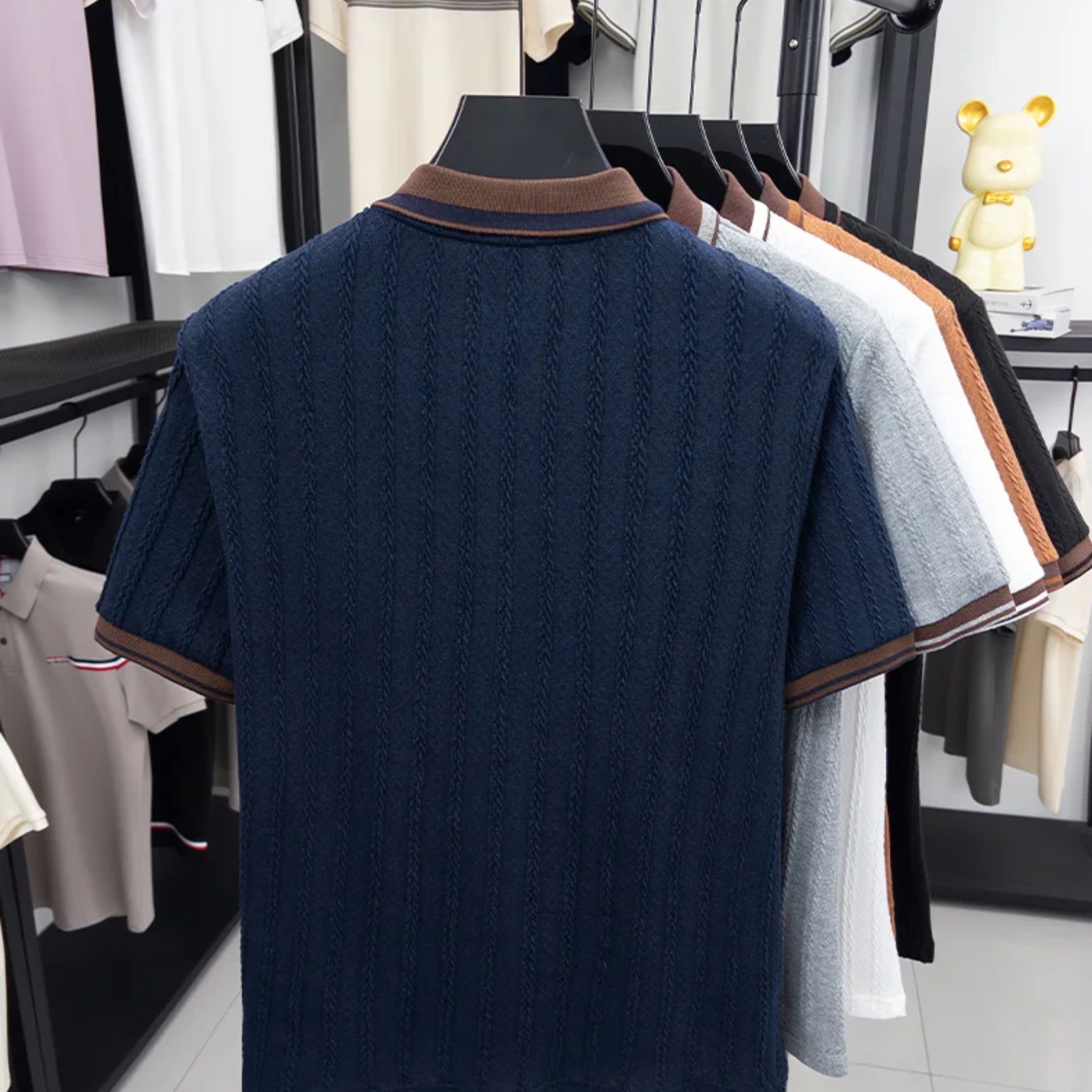 Rear studio view of the navy blue short-sleeve knitted polo showing the clean shoulder lines and brown trim collar.