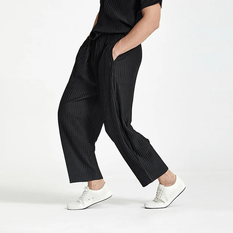 Side shot of a man styling black ankle-length pleated streetwear pants in motion