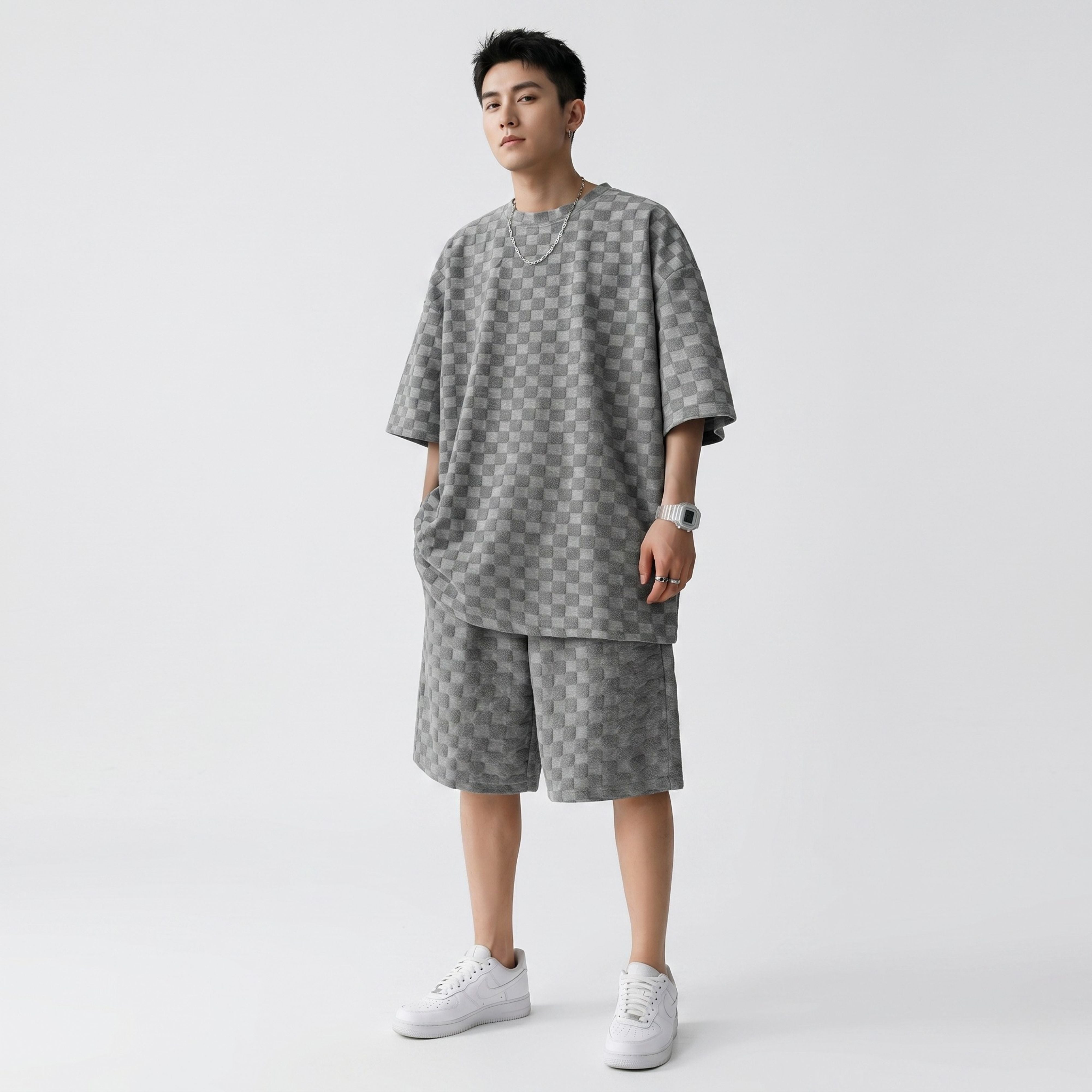 A male model wearing the grey checkerboard pattern two-piece set, displaying the modern Korean high street loose proportions