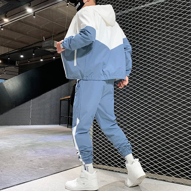 Rear dynamic shot of a male model presenting the light blue and white block pattern details on the athletic jacket and training pants