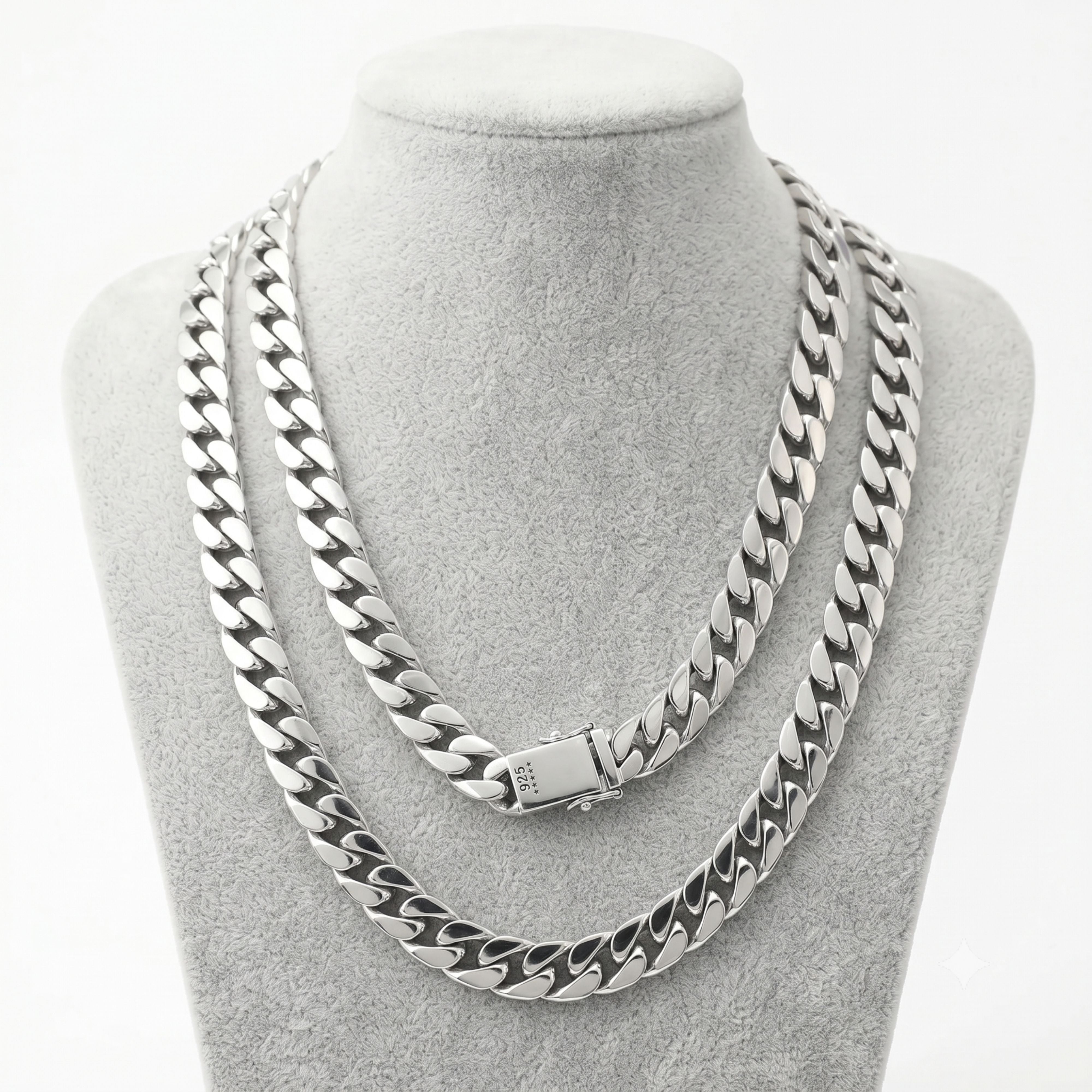Two thick men's silver Miami Cuban link chains of varying lengths displayed on a grey velvet jewelry bust.