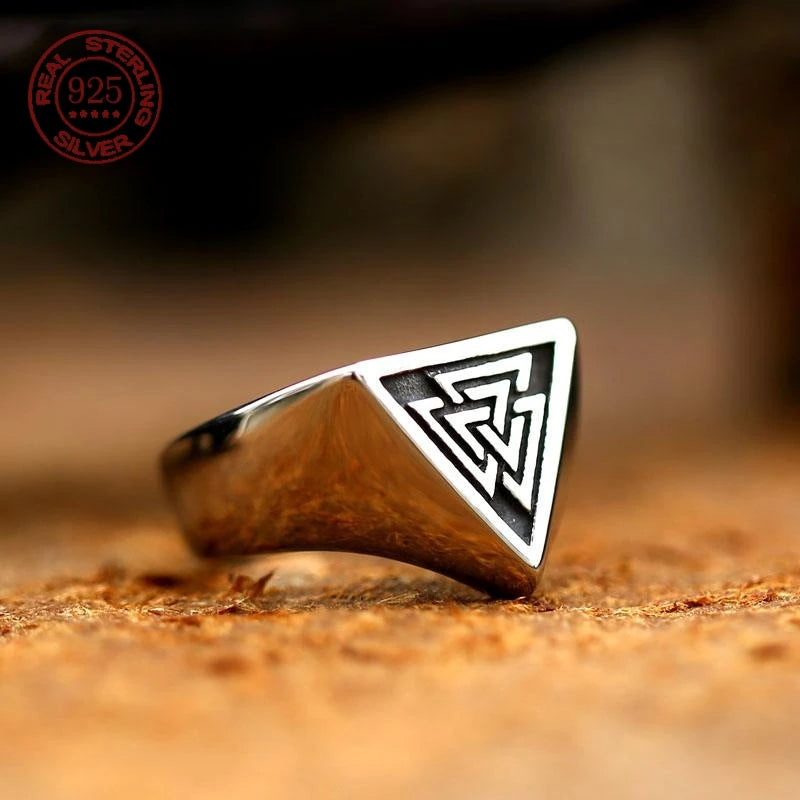 Men's silver Valknut Viking ring resting on a warm wooden surface, highlighting the polished metal and engraved Norse symbol.