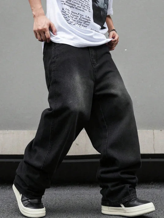 Front view of a man wearing modern micro flared loose jeans in washed black denim for an American vibe streetwear look