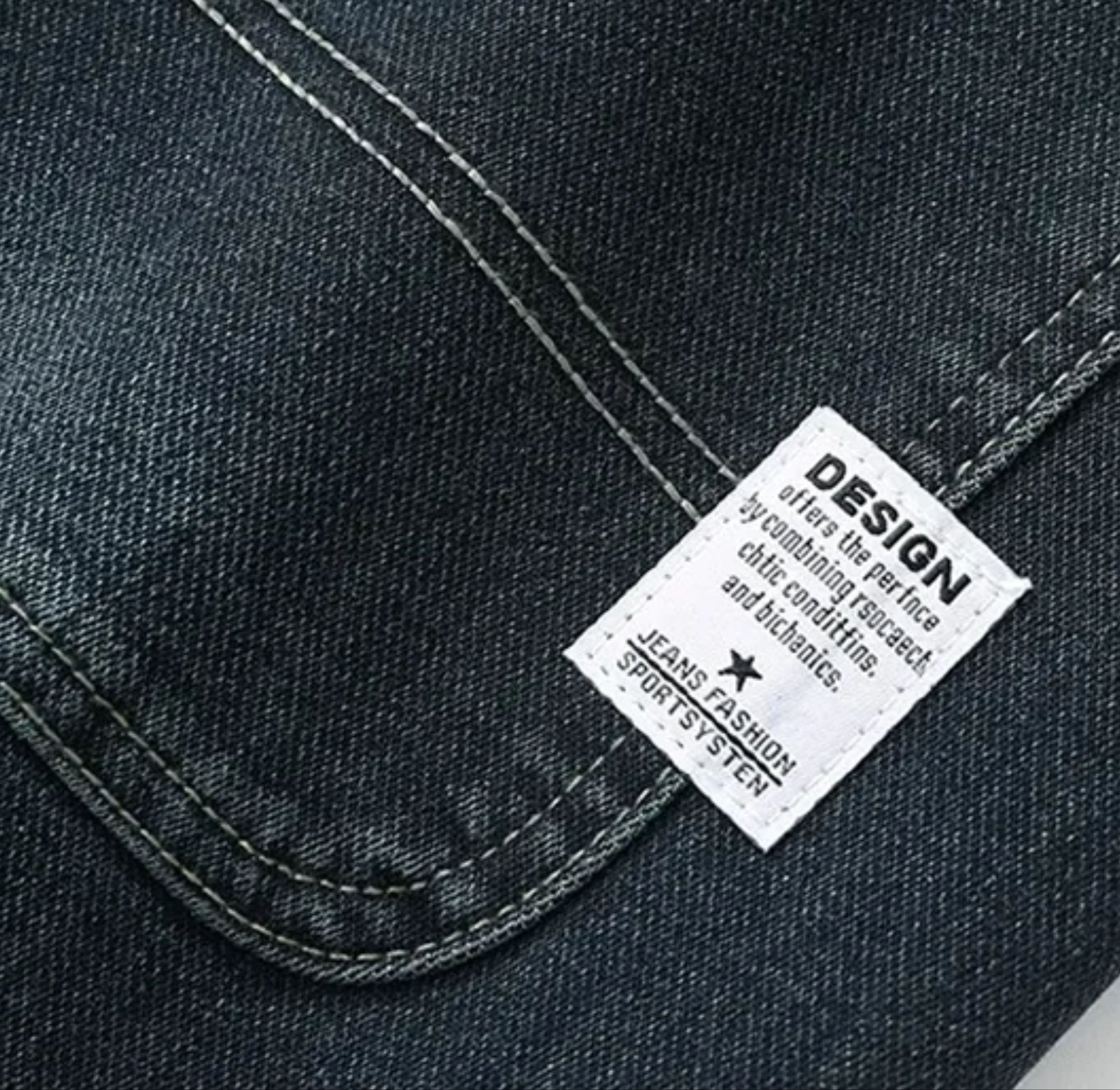 Macro close-up shot of the white typographic design fabric label stitched on the back pocket, highlighting the neat dual-thread pocket corner reinforcement