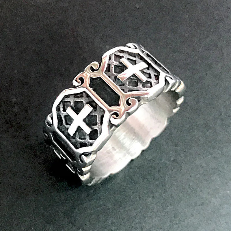 Vintage silver iron cross ring for men with detailed carved patterns resting on a dark grey surface.