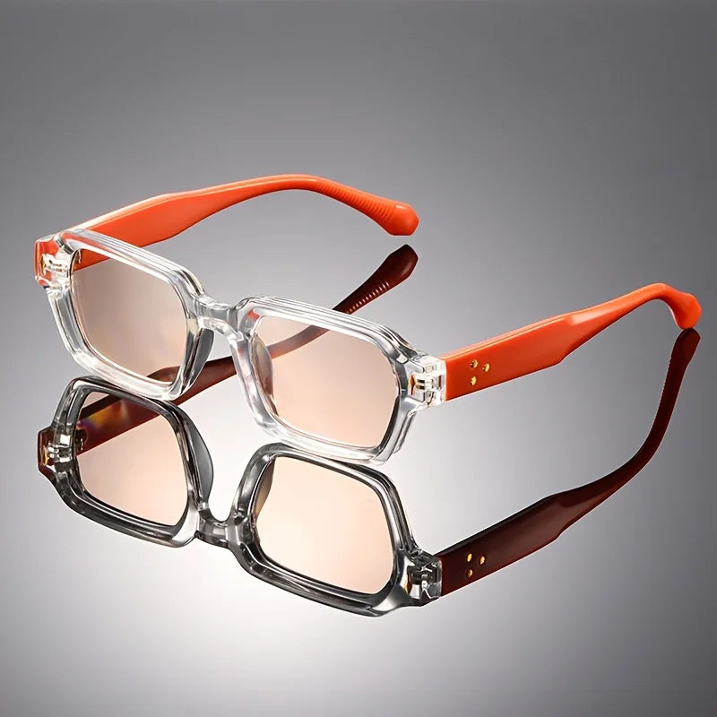 Retro chunky rectangular sunglasses with a clear front frame, orange temples, and light pink lenses reflecting on a dark background.