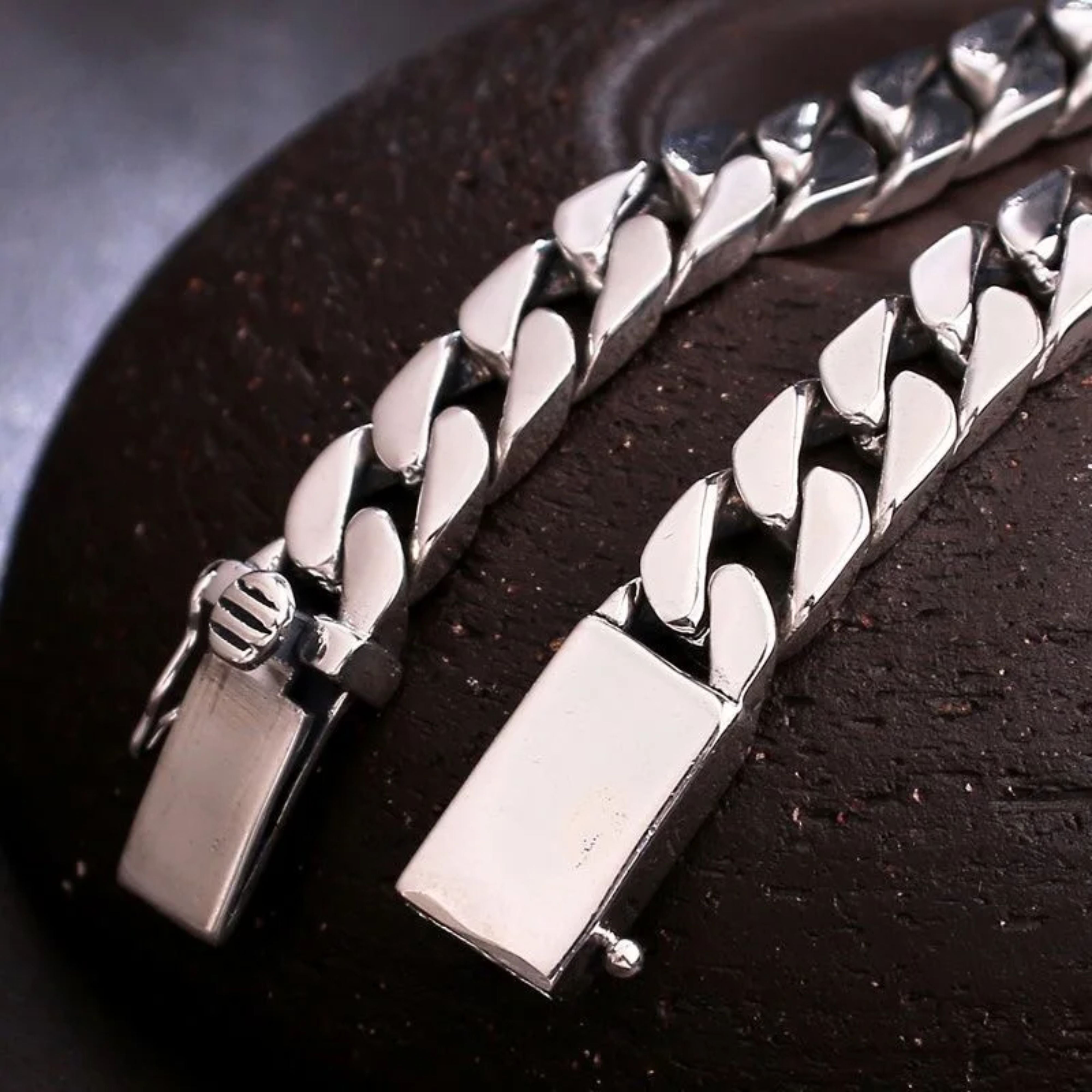 Detailed macro view of the open double safety box clasp of a thick silver Cuban chain.