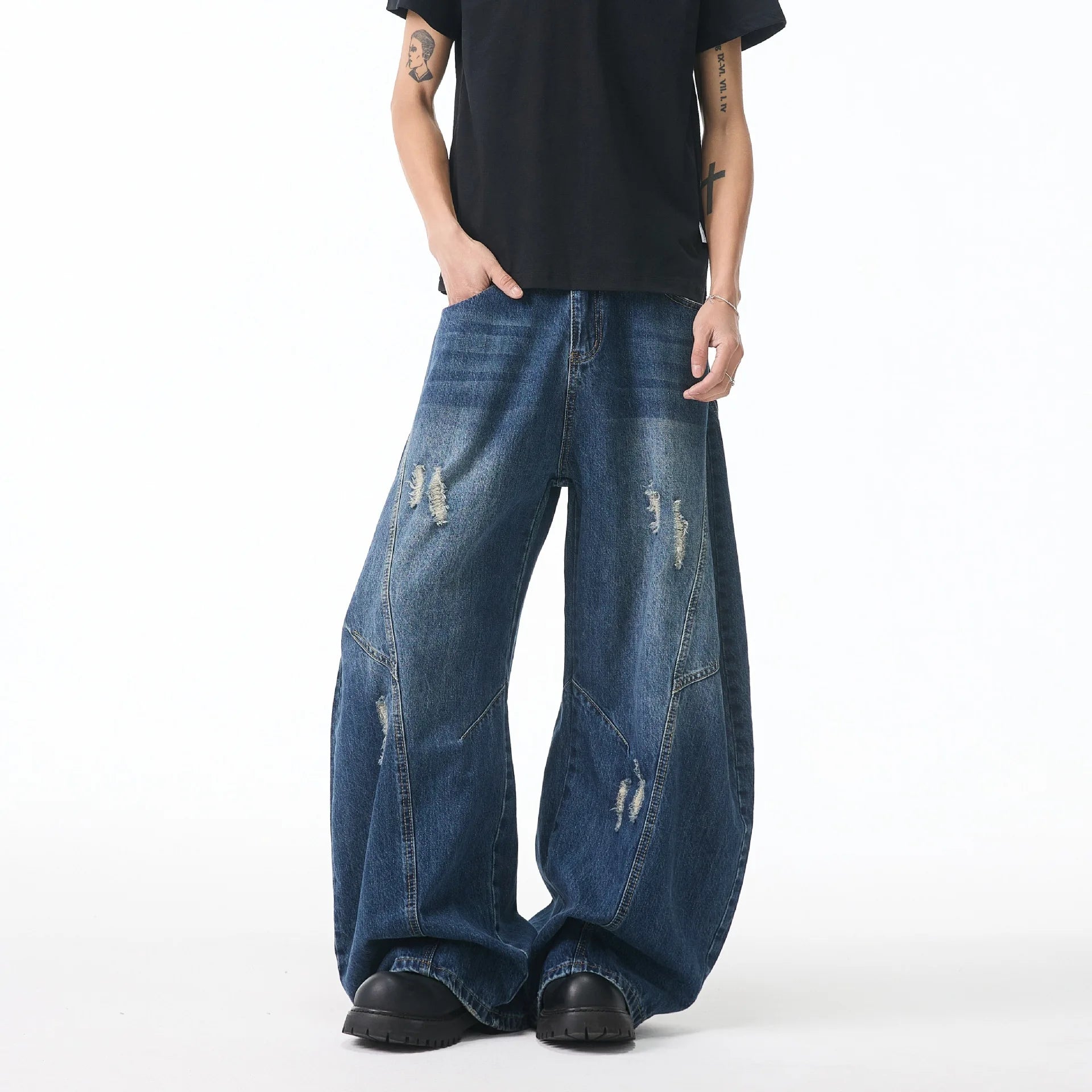 Front view of a model wearing medium blue wide-leg jeans featuring distinct geometric fabric patches and loose fit styling
