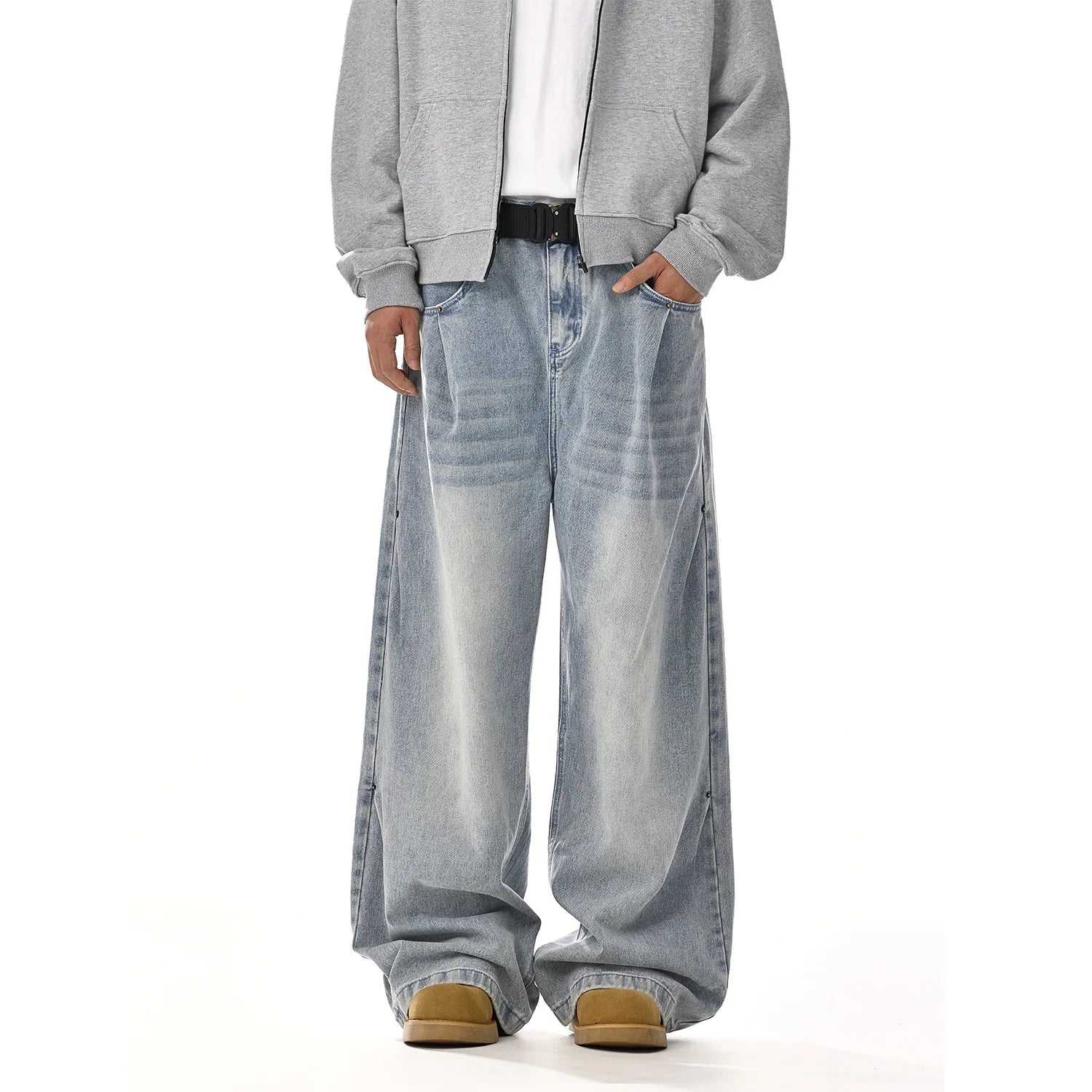 Model in gray zip hoodie styling a pair of faded light blue baggy denim pants with a black leather belt