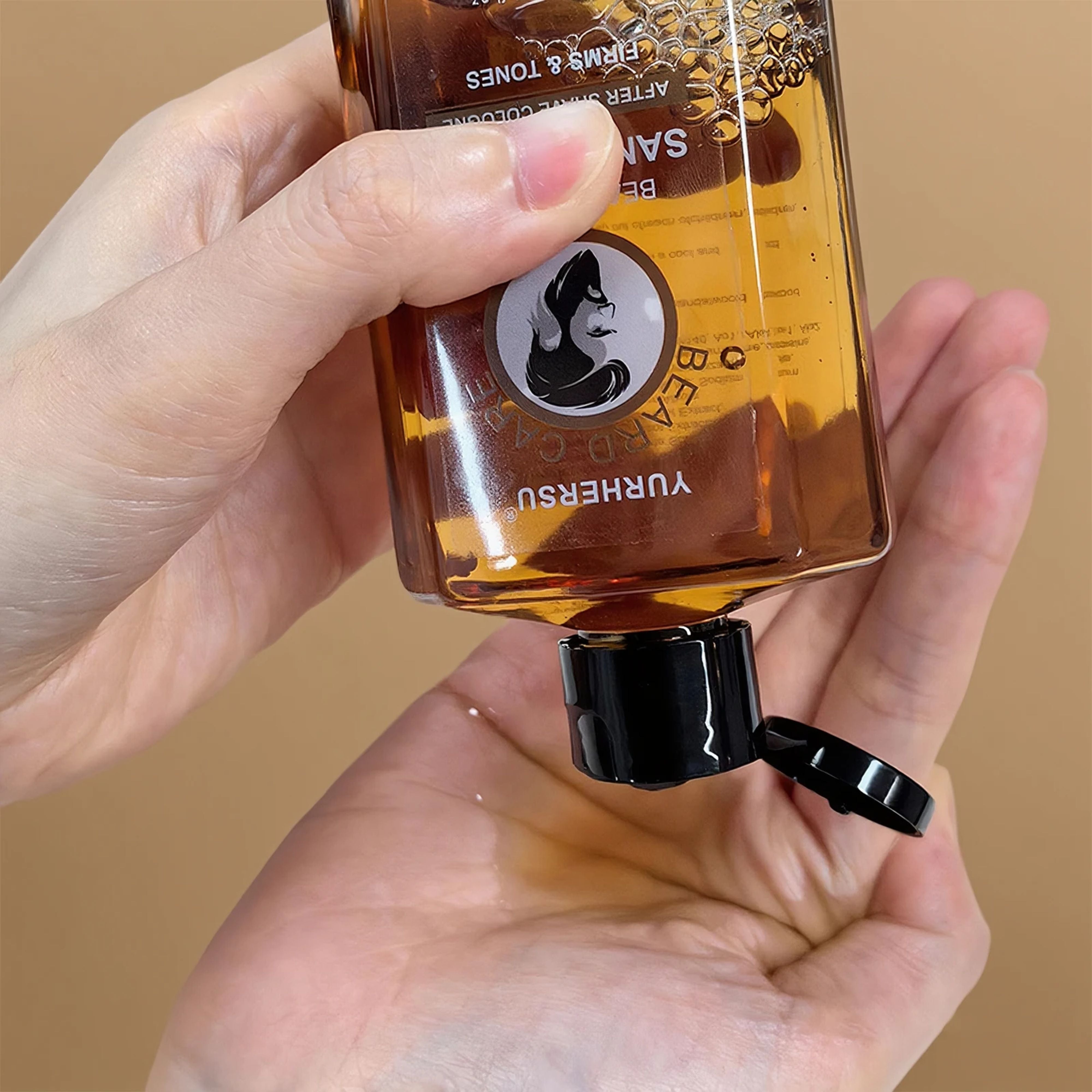 Close-up shot of a hand tilting the transparent amber Yurhersu aftershave bottle to dispense the liquid lotion
