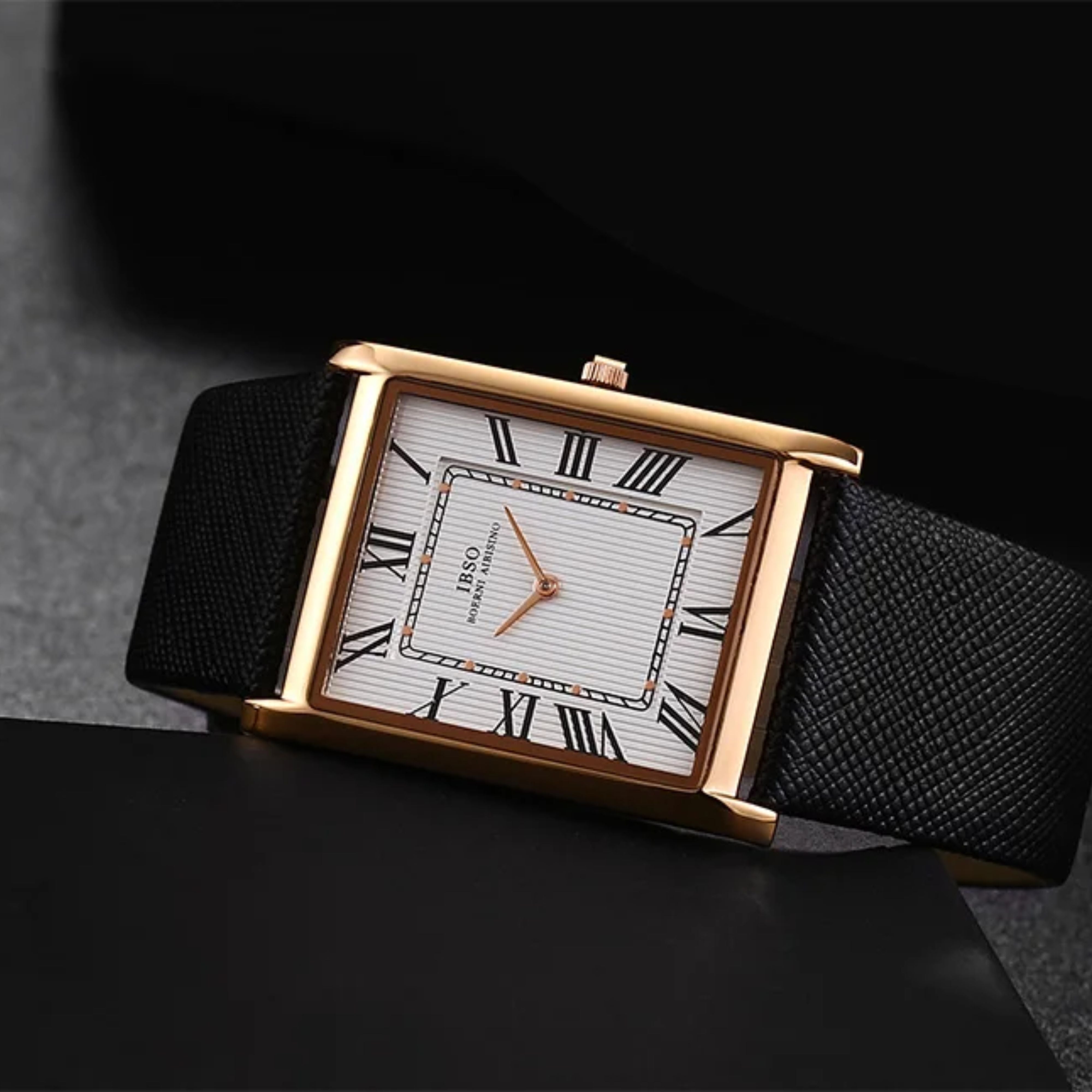 Moody studio product shot of the IBSO rose gold rectangle watch with a white dial and roman markings resting gracefully over a dark matte surface