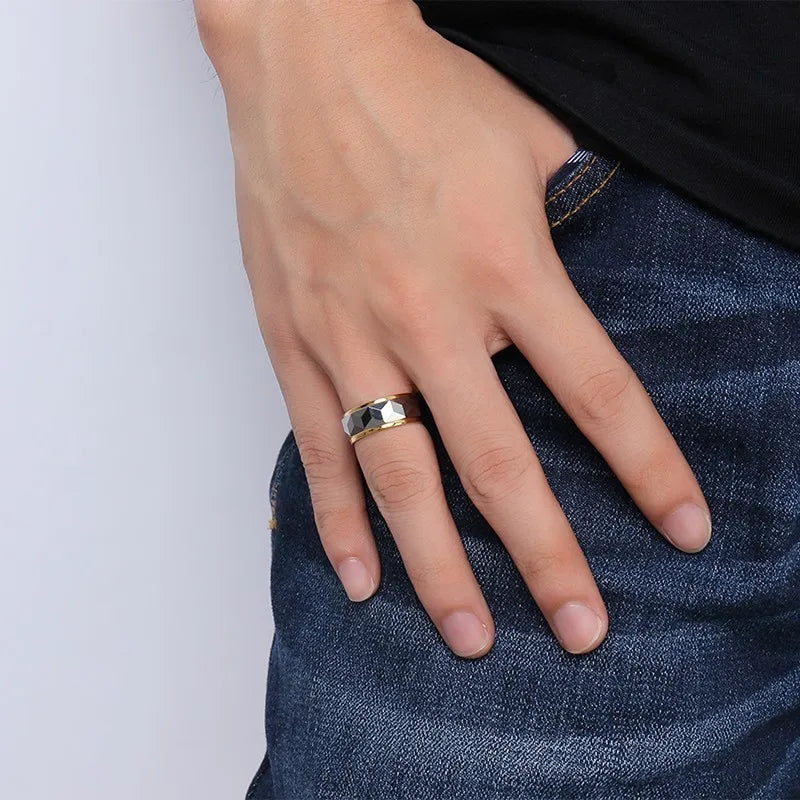 Close-up of a man with his hand on his denim jeans pocket, wearing the wide Meaeguet faceted silver and gold tungsten ring on his middle finger