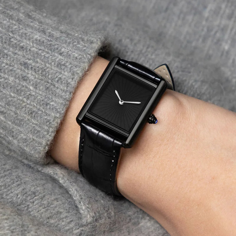 A person wearing the ZBJP minimalist all-black square watch on their wrist, styled with a casual grey sweater