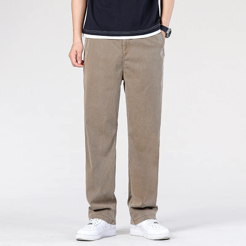 Front view of a model wearing the loose straight coffee khaki Lyocell trousers styled with a minimalist black shirt and white sneakers