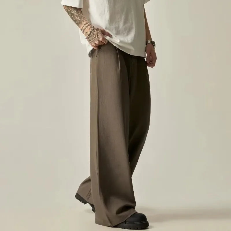 Side view of a model styling olive wide-leg pleated trousers with a white t-shirt and chunky shoes