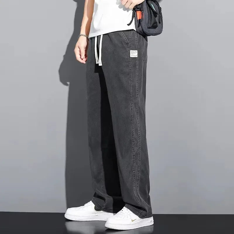 Full length side profile of a model wearing dark gray soft Lyocell straight-leg casual jeans with white shoes