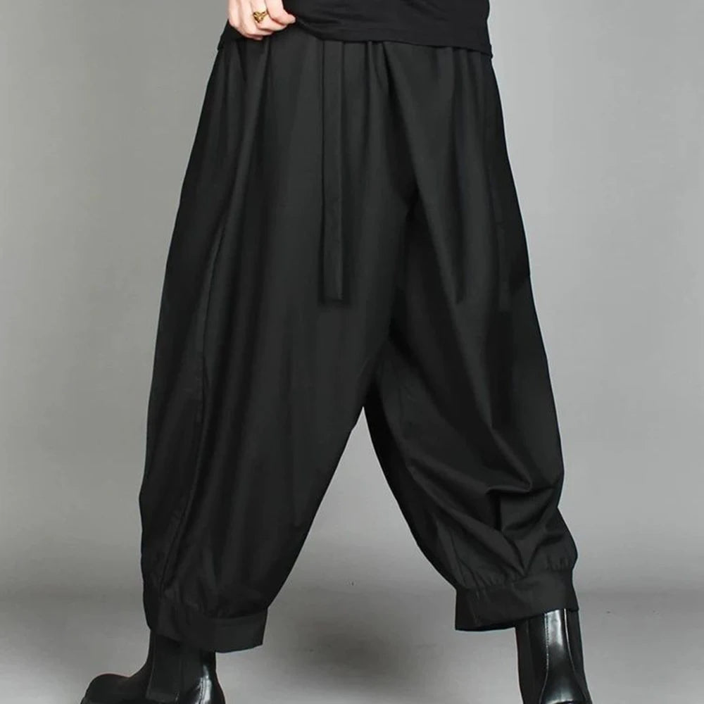 Side view of a man styling loose tapered leg pants with a minimalist streetwear aesthetic