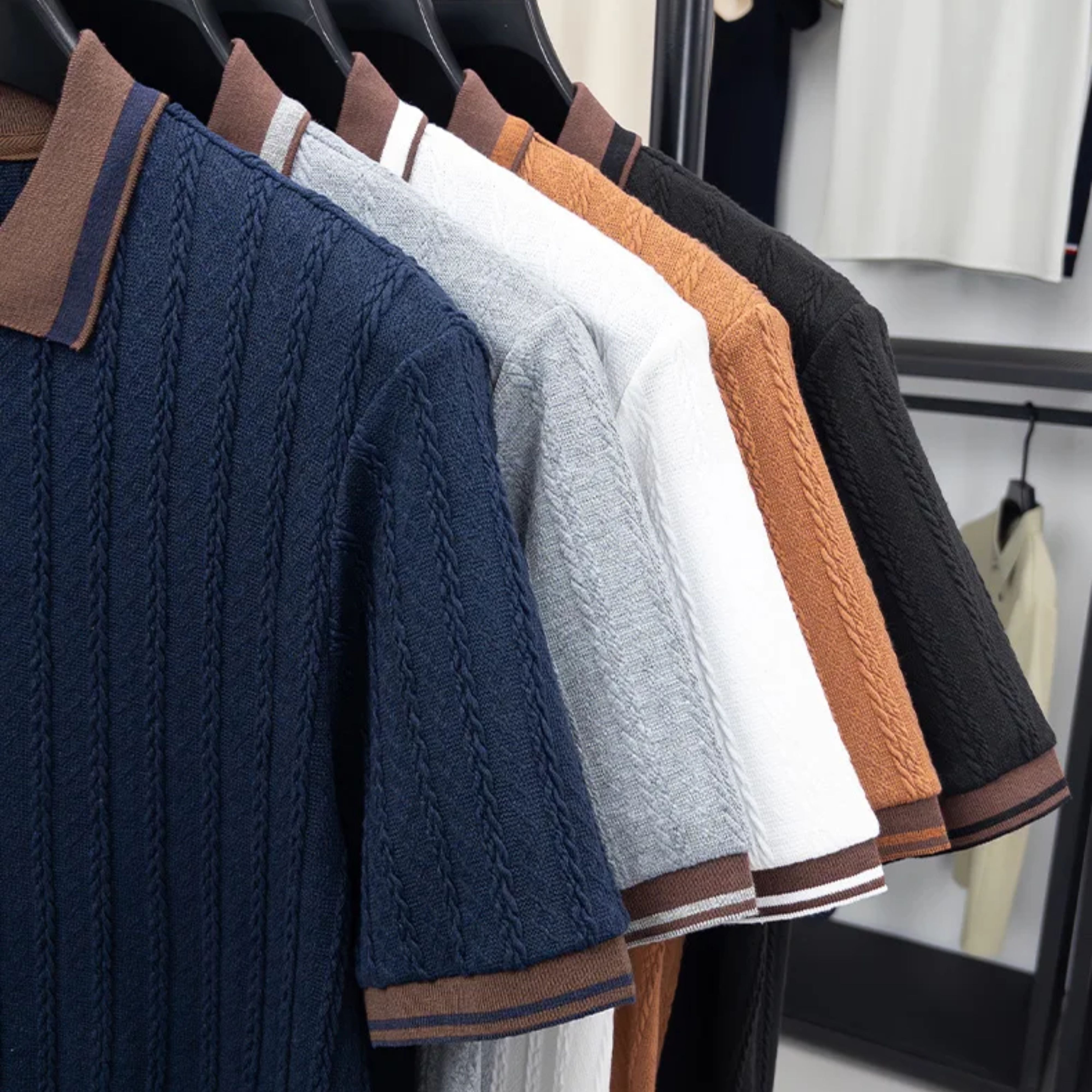 Side angle view of multi-color vintage men's knit polo pullovers hanging neatly in a fashion boutique.