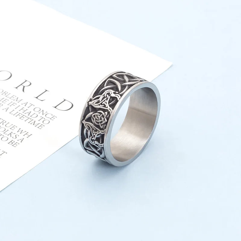 Men's silver Celtic wolf ring standing upright on a light blue background next to a text card.
