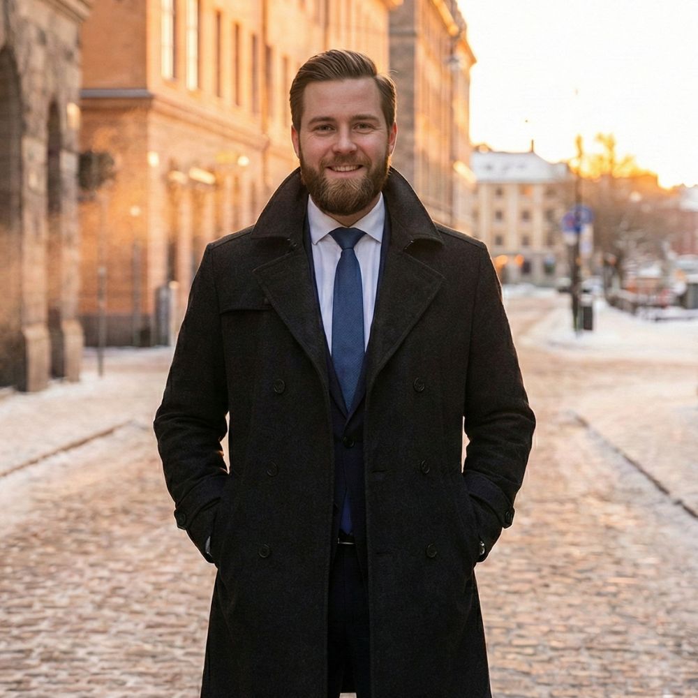 Man wearing a premium men’s trench coat in a winter city at sunset, representing the trench coat collection.
