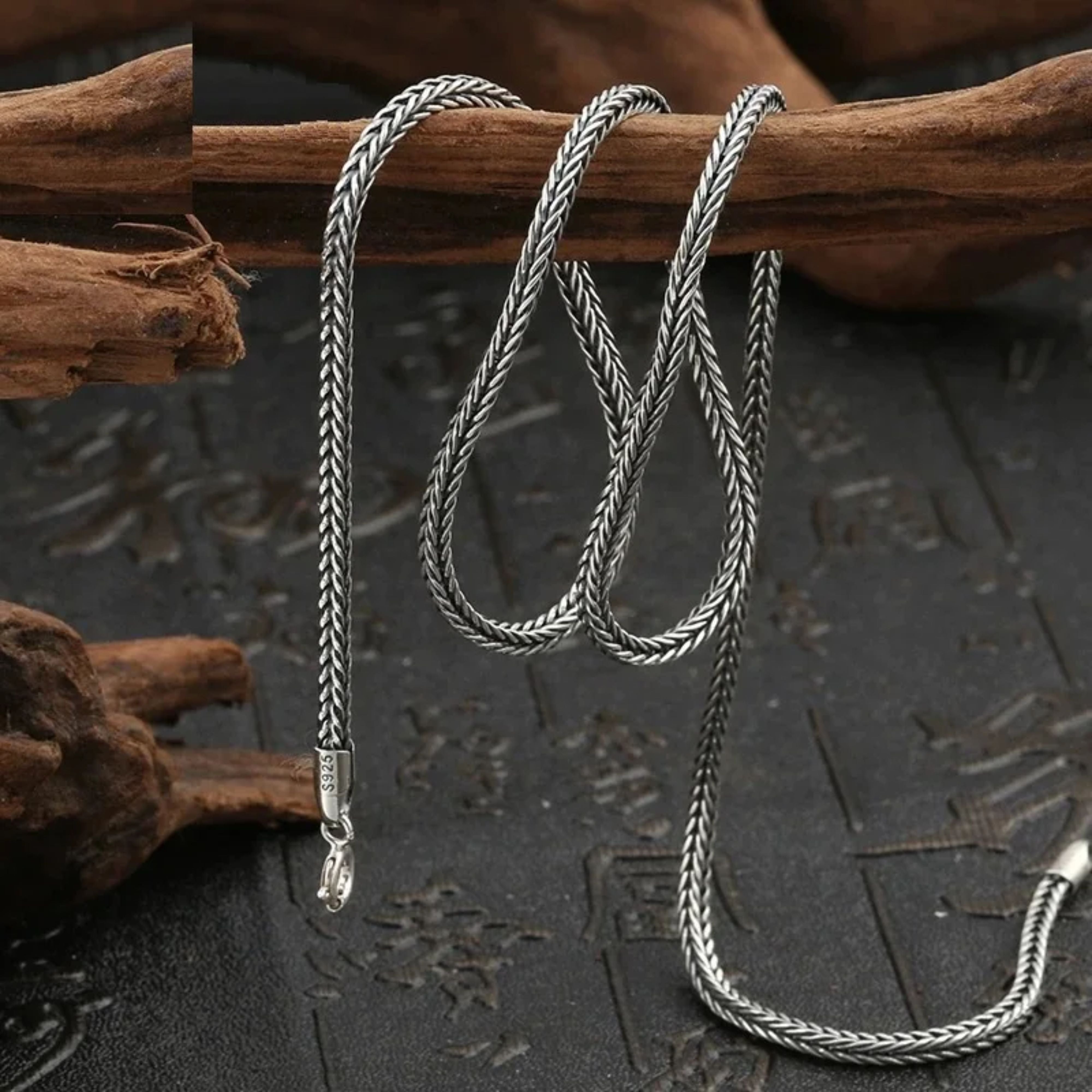 Oxidized silver foxtail sweater chain draped naturally over dark textured driftwood.