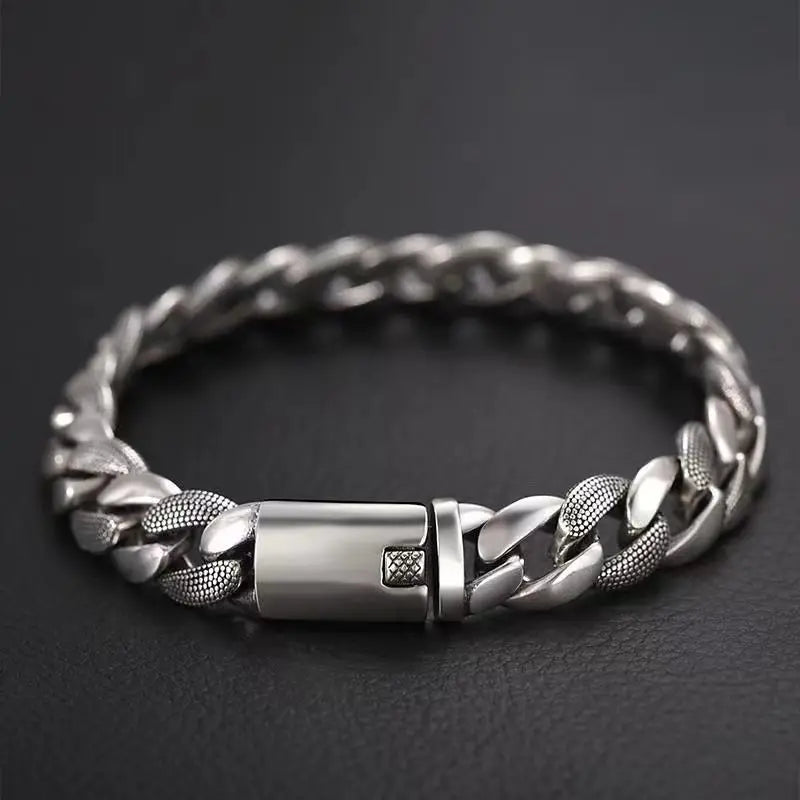 Closed silver Cuban link bracelet resting on a dark surface, highlighting the blank engravable box clasp.